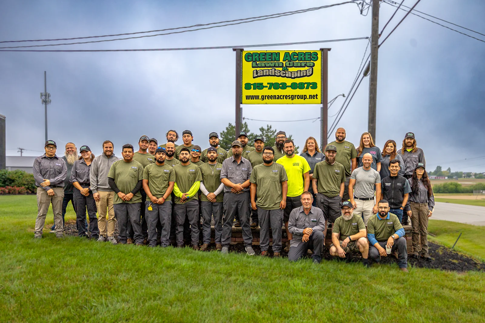 Green Acres Lawn Care & Landscaping full crew team photo gathered under company sign