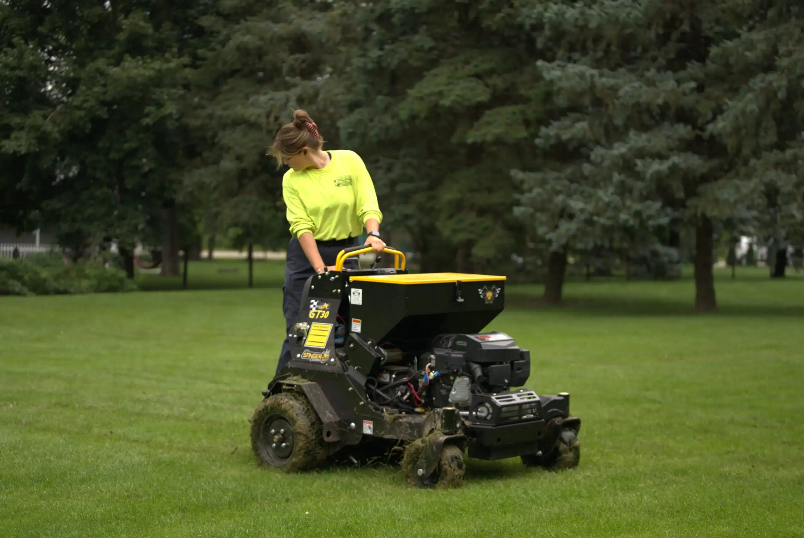 Green Acres crew member performing lawn aeration service with professional stand-on aerator on residential property