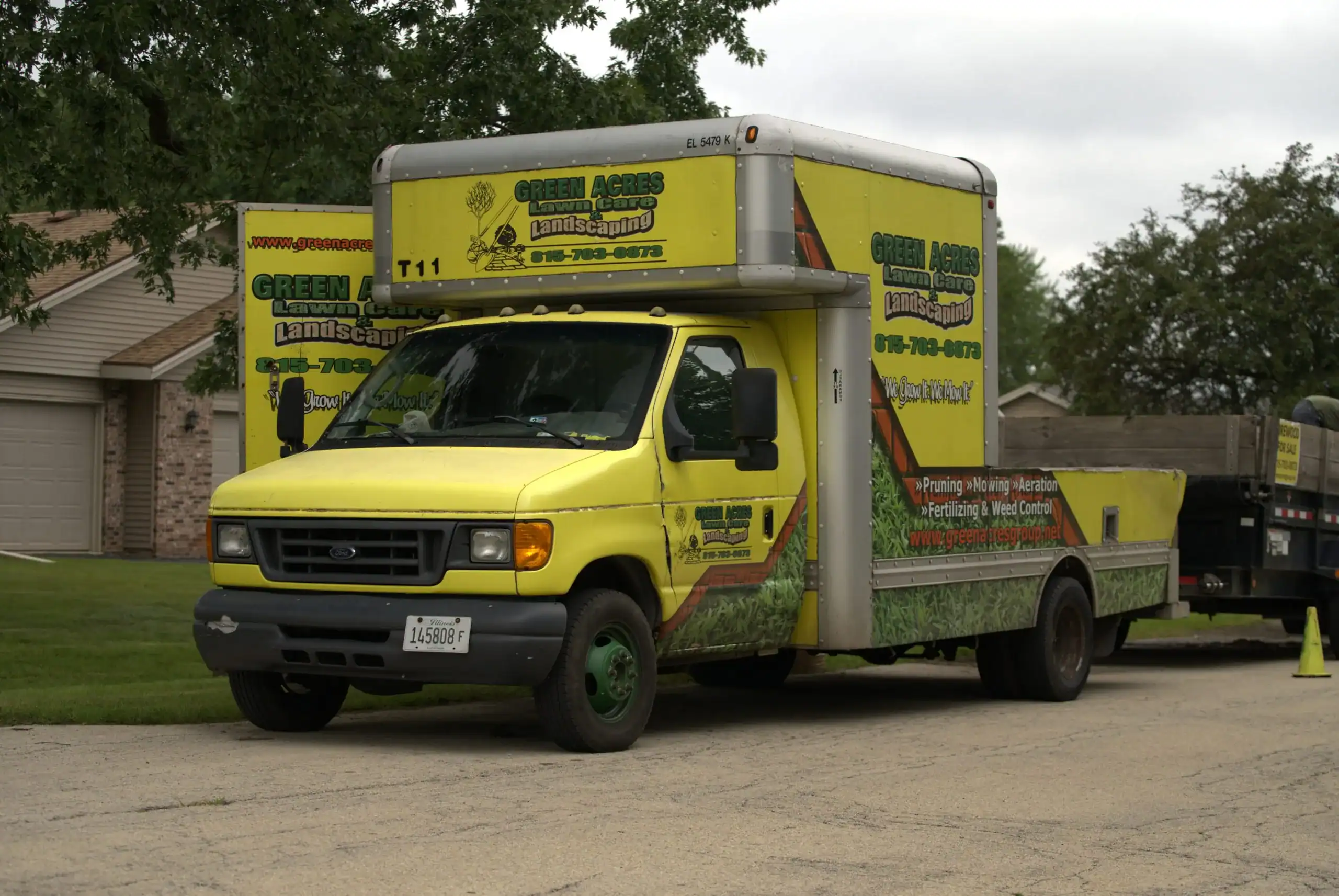 Green Acres Landscaping yellow branded service truck parked in residential neighborhood driveway