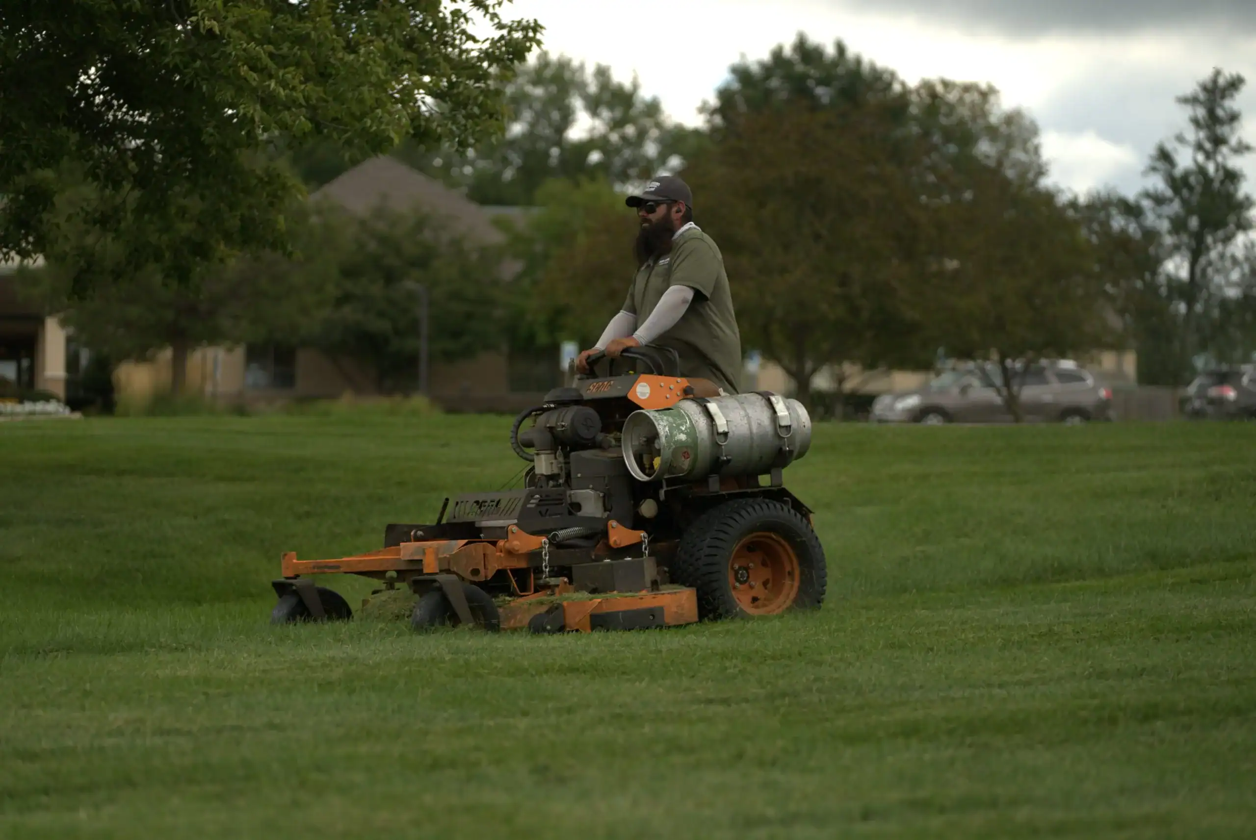 Green Acres crew member operating commercial stand-on mower on residential lawn