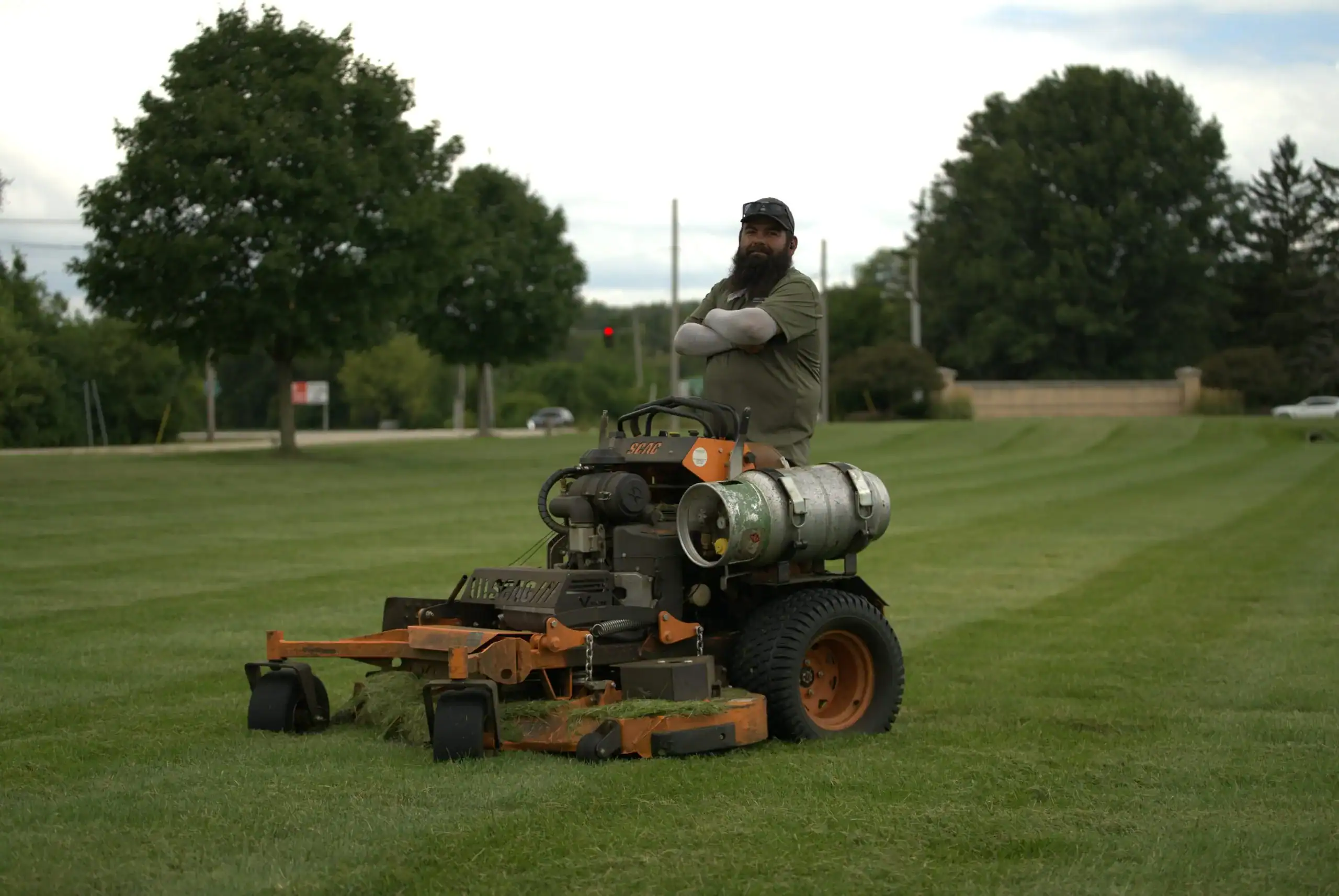 Green Acres crew member operating commercial stand-on mower on residential lawn