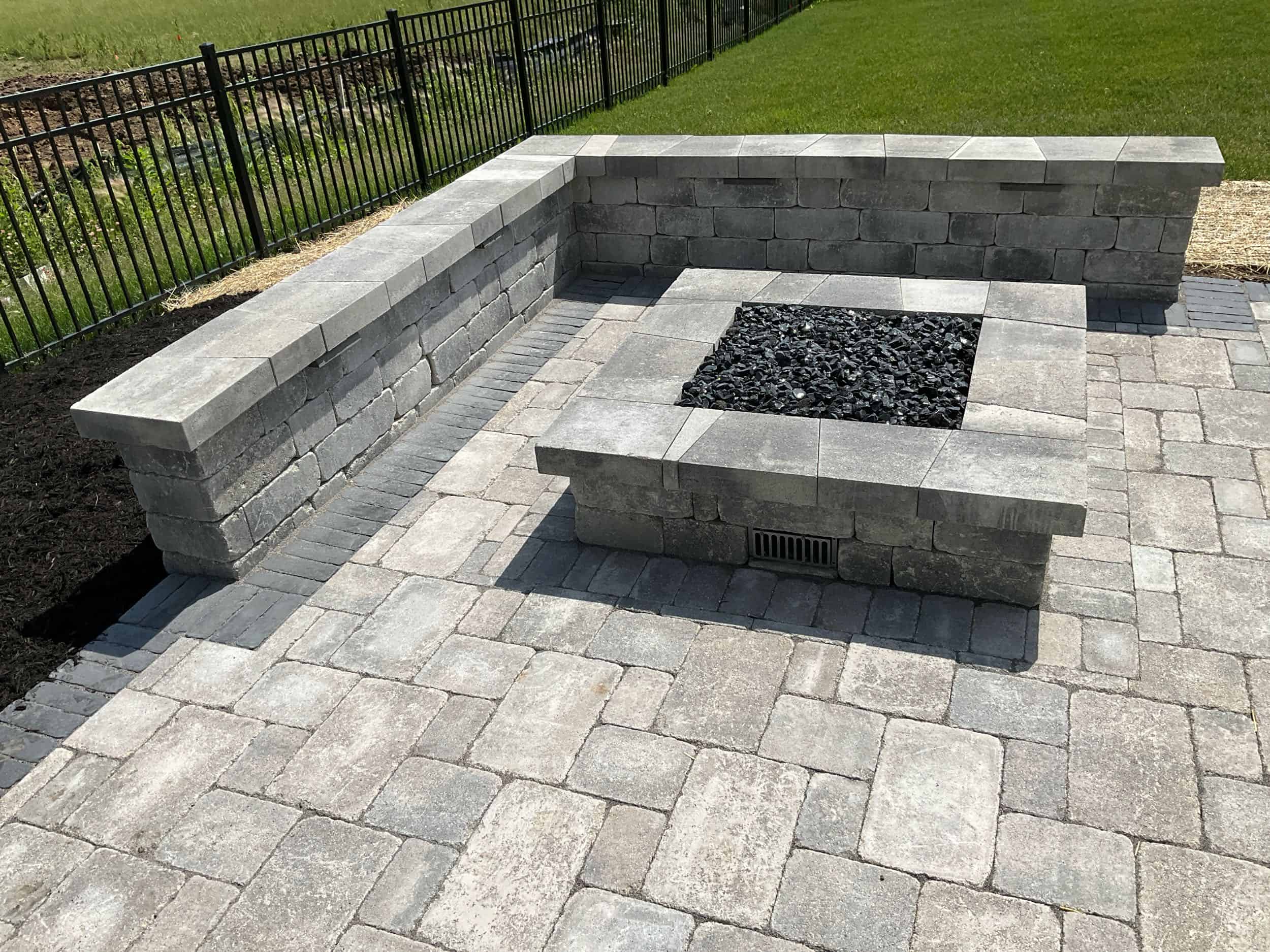 Green Acres completed paver patio installation with built-in fire pit and seating wall