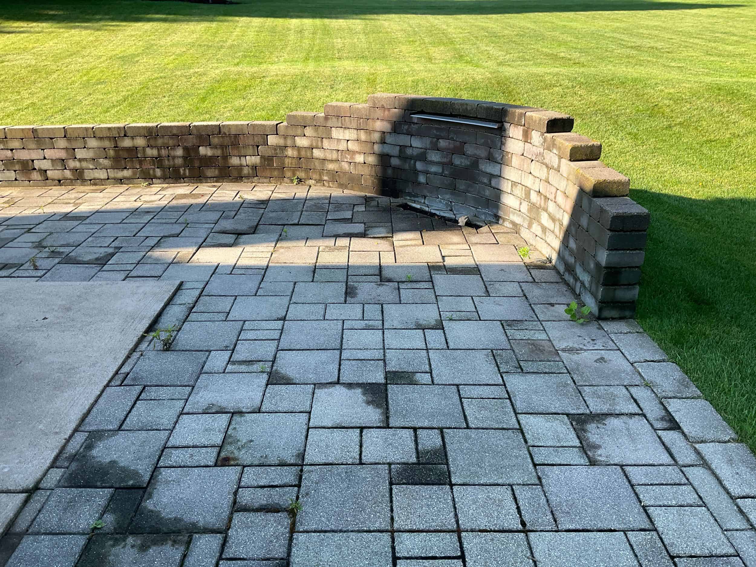 Green Acres completed paver patio installation with decorative brick retaining wall and manicured lawn